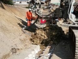 Ouvrier pied de mât et foreuse tarière creuse en travail.